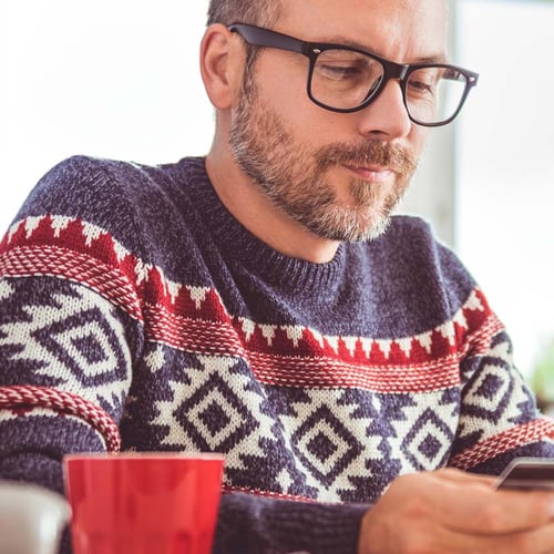 man in a Christmas sweater looking at his phone